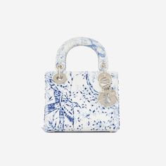 Named after and once gifted to Princess Diana upon a trip to Paris in 1995, the Lady Dior is undoubtedly one of the most acclaimed, desired and historic handbags of all time. The ultimate must-have for any women with a love for luxury and an appreciation for history, no luxury handbag collection is truly complete without a Lady Dior. SPL Exterior White and blue printed calfskin Bead embroidery Dior Jardin Motif Champagne tone hardware Dior logo charms Two top handles Detachable shoulder strap Protective feet at base Flap closure 2022 production Brand new condition Interior Suede interior One main compartment One slip pocket Brand new condition Sold with box, dustbag, strap SPL Height 15cm Width 17cm Depth 7cm Delivery 5-8 or 10-15 working days Please note that during high season and Sale p Lady Dior Mini, Tas Lv, Tas Hermes, Mini Lady Dior, قلادات متدلية, Dior Cruise, French Luxury Brands, Sacs Design, Luxury Bags Collection