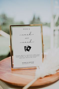 a sign that is on top of a wooden table next to a white and black feather