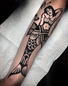 a black and white tattoo on the arm of a person with a fish in it