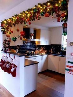 a kitchen decorated for christmas with stockings hanging from the ceiling