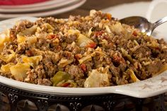 a white bowl filled with meat and vegetables on top of a table next to a fork