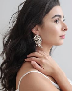 a woman with long black hair wearing large white earrings on her neck, looking off to the side