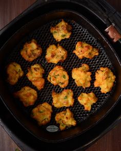 an air fryer filled with tater tots on top of a wooden table