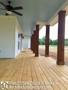 an empty porch with columns and ceiling fan