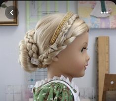 a doll with blonde hair and braids on her head, wearing a green dress