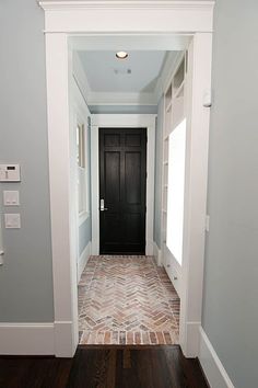 an empty hallway with a black door and white trim on the walls is seen in this image