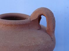 a clay vase with a curved handle on a blue background