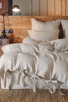 an unmade bed with white linens and pillows on top of the headboard