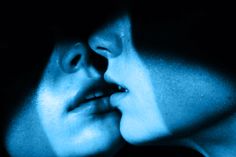 two people are kissing in the dark with blue light coming from their faces and behind them