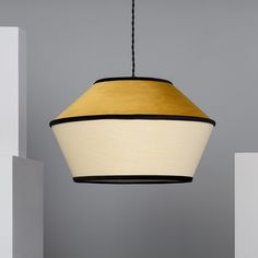 a yellow and white light hanging from a ceiling fixture in a room with grey walls