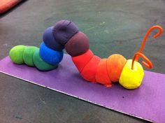 a very cute colorful caterpillar laying on top of a purple mat