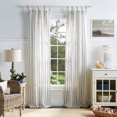 a living room filled with furniture and a large window covered in white striped drapes