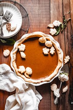 a pie sitting on top of a wooden table next to a white plate and silverware