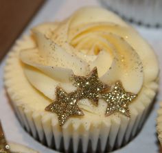 two cupcakes with white frosting and gold stars