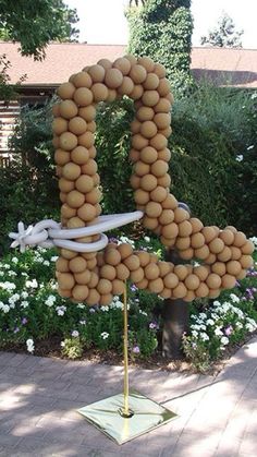 a large letter made out of potatoes sitting on top of a metal pole in the middle of a garden