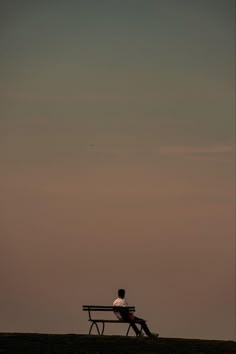 a man sitting on top of a bench next to a kite flying in the sky