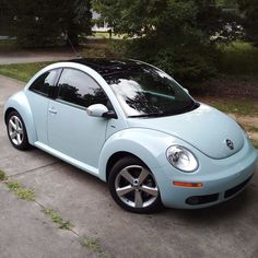 a light blue car parked on the side of a road next to trees and grass