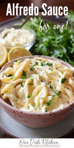 a bowl of macaroni and cheese on a plate next to lemon wedges