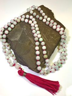 108 beaded natural Jadeite Mala Necklace  Gems: 506ct Jadeite 8mm plain round gemstones and 10.3 Rose Quartz Guru bead Length 24" inches  A Mala Necklace Mala Beads are more than just pretty necklaces. Each element of a Mala Necklace carries a meaning. Learn more about each part of a Mala Necklace and how it can help you on your own journey of meditation and intention setting. 108 Beads Malas always have 108 Beads. According to traditional Buddhism, 108 represents the number of mortal desires of Spiritual Jade Jewelry With 108 Beads, White Jade Beaded Necklaces With Round Beads, Spiritual Round Jade Beaded Necklaces, Spiritual Round Jade Beaded Necklace, Jade Bead Necklaces For Meditation, Spiritual Hand-strung Jade Beaded Necklace, Spiritual Jade Beaded Necklace, Spiritual Single Strand Jade Beaded Necklace, Beaded Jade Necklaces With Gemstone Beads