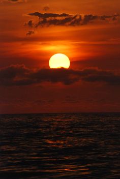 the sun is setting over the ocean with clouds in the sky and water around it