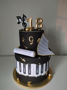 a black and white cake with musical notes on it's side, topped by a piano