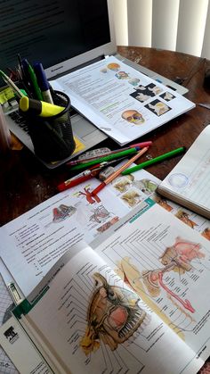 an open book sitting on top of a wooden table next to markers and pencils