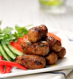 meatballs and vegetables on a white plate with a red fork next to the plate