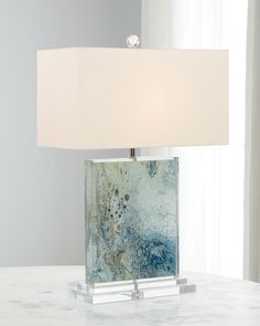 a lamp that is sitting on top of a table with a white shade over it