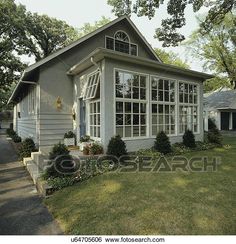 a gray house sitting on top of a lush green field