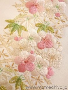 an embroidered design with flowers and leaves on the side of a white fabric material that has been stitched together