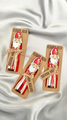 three christmas crackers with santa claus on them sitting on a white satin surface,