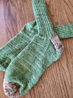 a pair of green socks sitting on top of a wooden floor