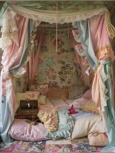 a canopy bed with pink and blue drapes on it's sides, surrounded by floral wallpaper