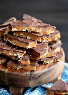 a wooden plate topped with pieces of chocolate covered pretzel barkle next to a blue and white napkin