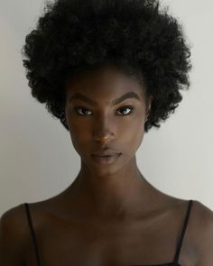 a woman with an afro is looking at the camera while wearing a black tank top