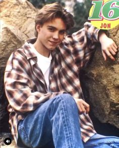 a young man sitting on top of a rock next to a pile of rocks with the number sixteen on it