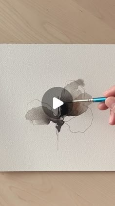 a person is holding a pencil and drawing a hole in the wall with watercolors