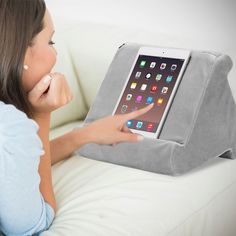 a woman laying on a couch with an ipad in her lap and pointing at the screen