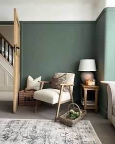 a living room with green walls and a white chair next to a rug on the floor