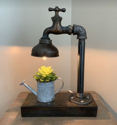 a metal watering can with a yellow flower in it on top of a wooden table