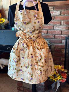 an apron dress is hanging on a mannequin in front of a brick wall