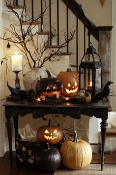 a table with pumpkins and candles on it in front of a stair case filled with halloween decorations