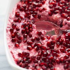 pomegranate in a white dish with a spoon inside the bowl, ready to be eaten