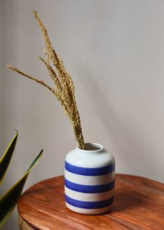 a blue and white vase sitting on top of a wooden table next to a plant