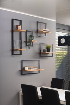 a dining room table with chairs and shelves on the wall