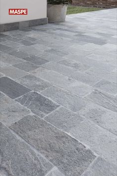 a stone walkway with a sign that says maspe on it and a planter in the background