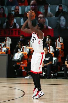 a man holding a basketball in his right hand and looking up at the sky while standing on a court