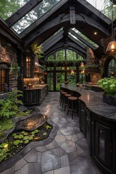 an outdoor kitchen with lots of plants in the center and stone flooring on the outside