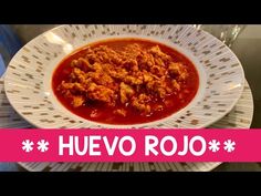 a white plate topped with meat covered in sauce on top of a table next to a pink ribbon