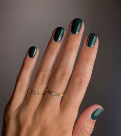 a woman's hand with green manicures and a gold ring on it